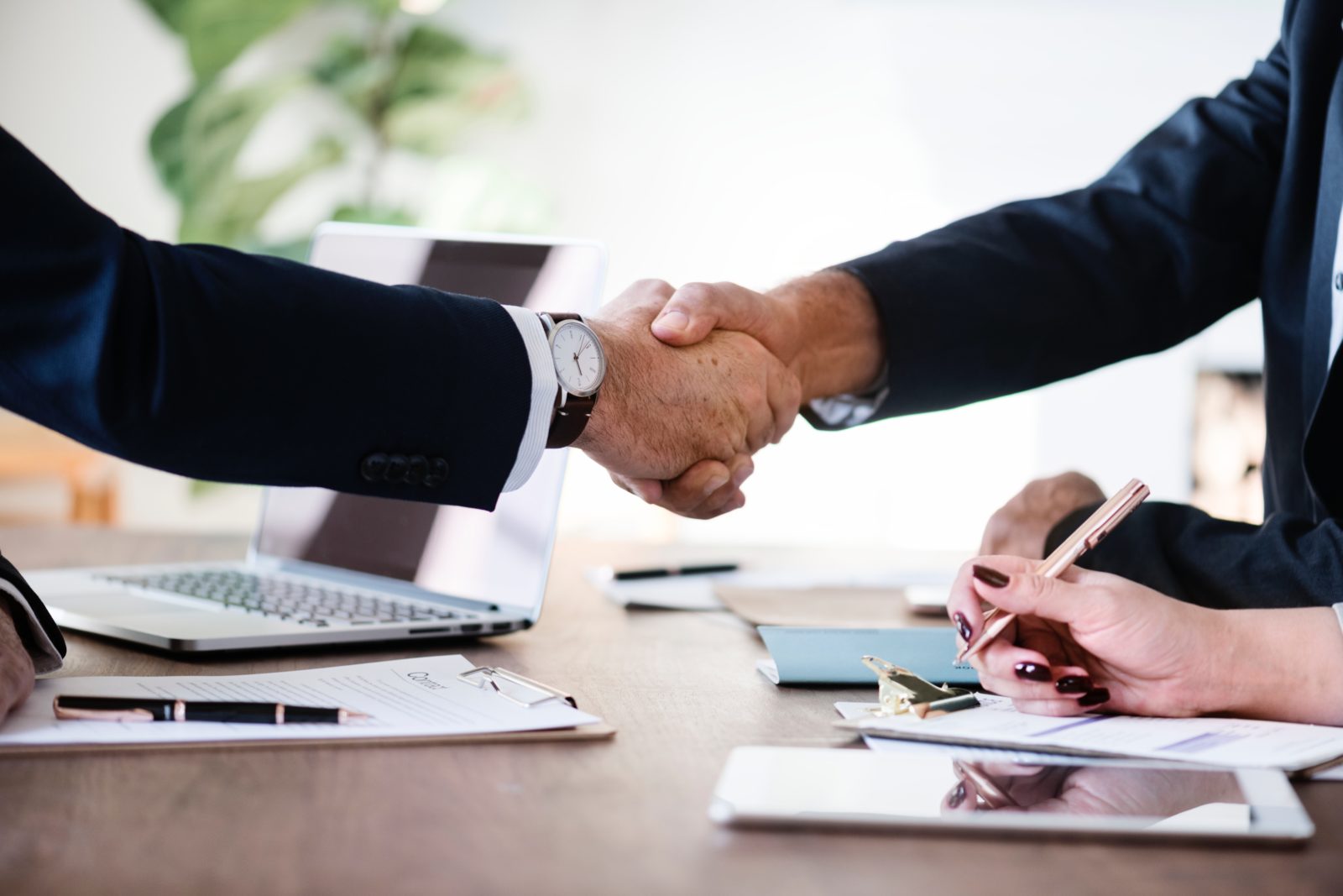 Two MegaPlanIT employees shaking hands over a table.