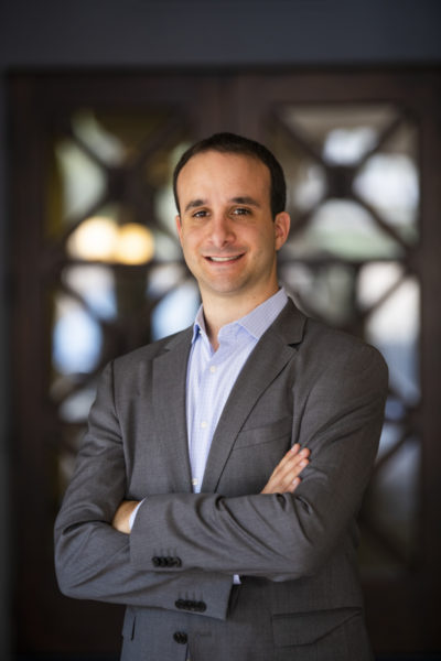 A MegaplanIT Manager in a suit standing with his arms comfortably crossed and a smile on his face.