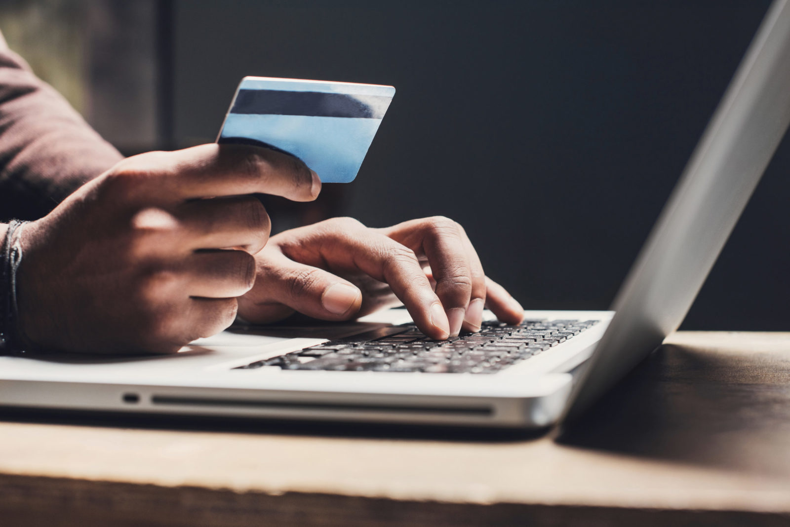 A man holding a credit card and using a laptop for PCI compliance.