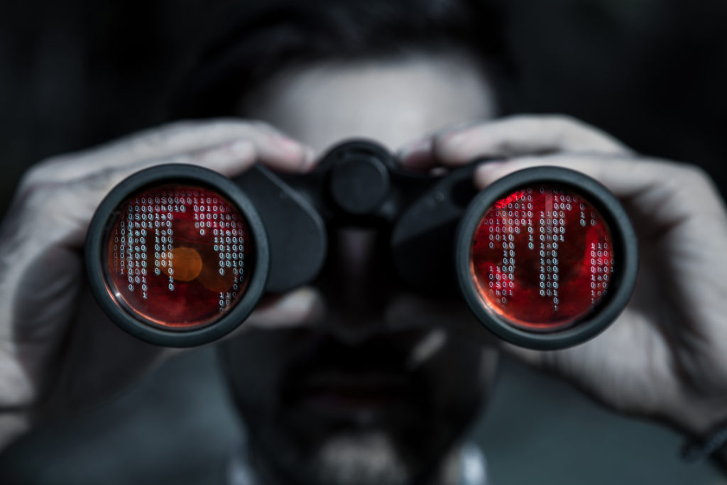 A man using binoculars with red lights for File Integrity Monitoring.