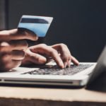 A man holding a credit card on a laptop, emphasizing cybersecurity and compliance.