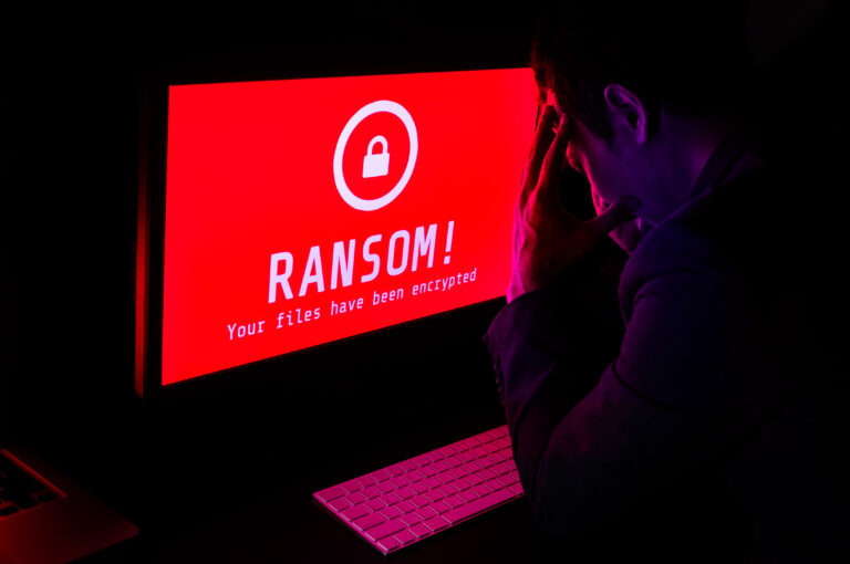 A man sitting in front of a computer screen assessing ransomware.