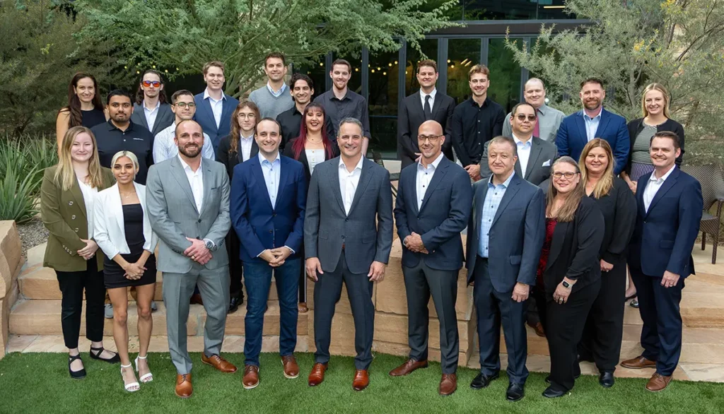 MegaplanIT company with the team outside in summer on green grass with trees in the background.