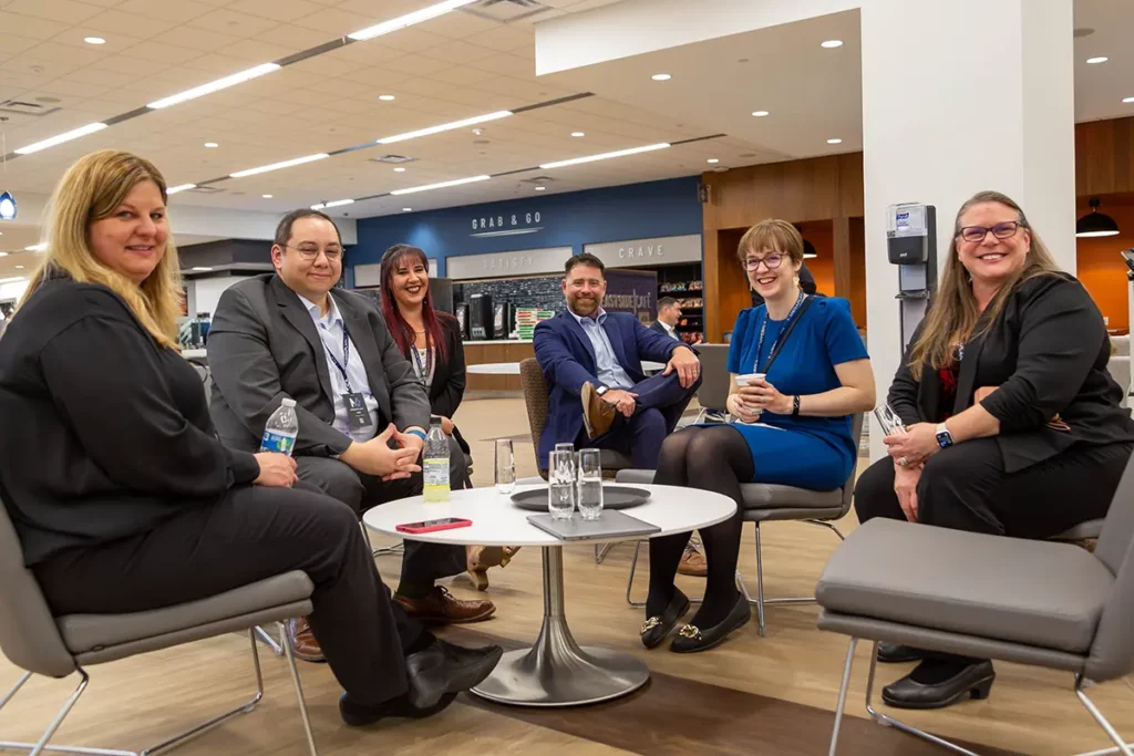 MegaplanIT friendly, professional employees sitting in a semi-circle in front of a white round coffee table enjoying a water break.